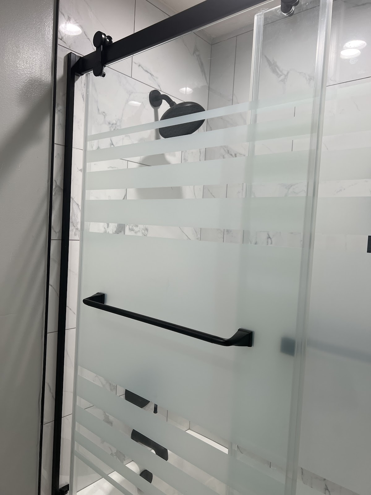 Frosted sliding glass shower door with black hardware