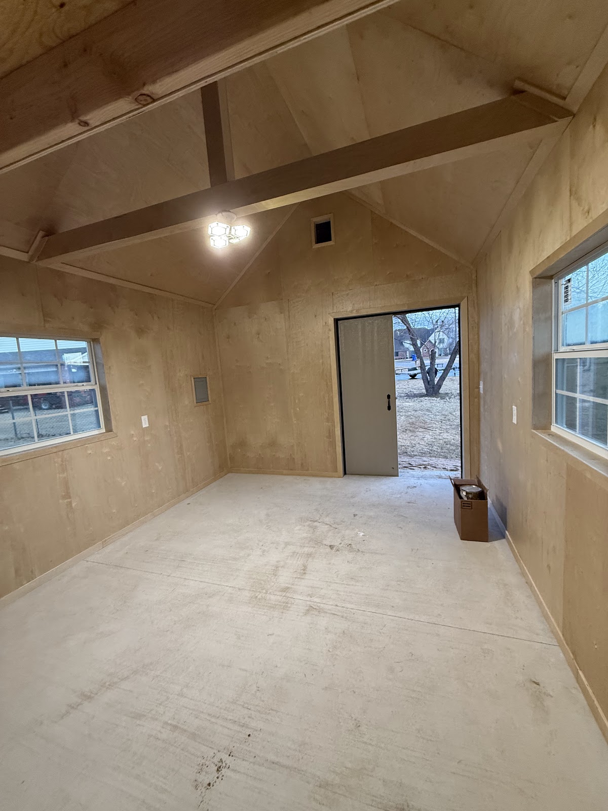 Finished shed interior with plywood walls and a loft beam